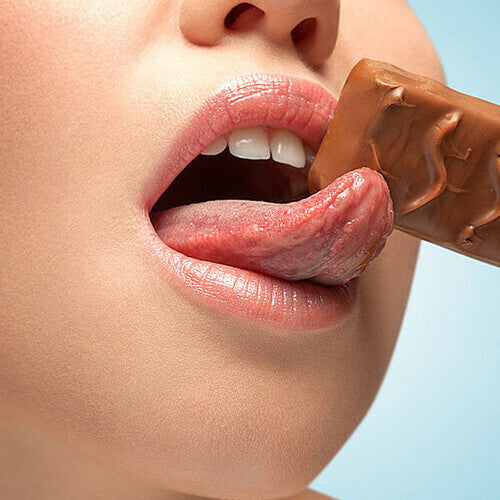 Close-up sensory image of a woman tasting chocolate to highlight the delicious, sugar-free edible flavor of the lubricant.